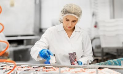 industry, food production and people concept - woman working at ice cream factory conveyor